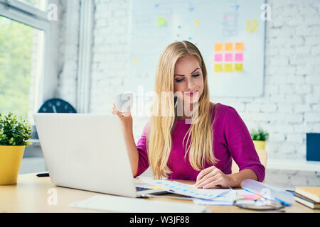 Attractive woman working with laptop at office browsing financial charts Stock Photo