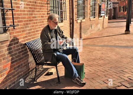 A real lost older senior man reading looking at map in Maryland while shopping on vacation in Naval Academy USA America tourist travel directions Stock Photo