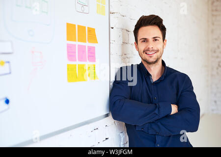 Happy young programmer, web designer standing at office Stock Photo