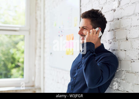Happy young man talking on the phone at modern office Stock Photo