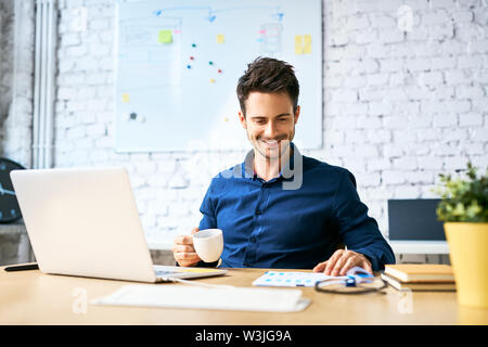 Young startup businessman drinking coffee and working using laptop and documents Stock Photo