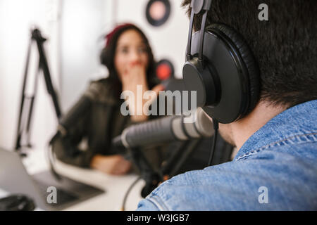 Man and woman in white shirts podcasters interview each other for radio podcast Stock Photo