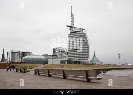 People walking along the waterfront at Willy Brandt Platz in Bremerhaven, Germany, with the Atlantic Hotel Sail City and Klimahaus museum in view. Stock Photo
