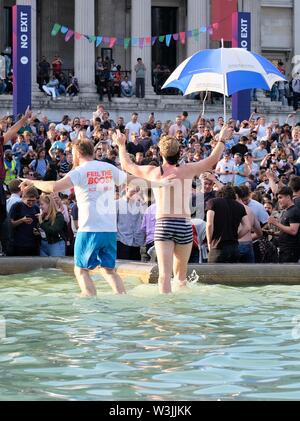 Two Cricket Fans Dance to Celebrate England's World Cup Victory in Trafalgar Square's Fountains with Crowd Watching in the Background Stock Photo