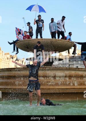 Cricket Fans Celebrate England's World Cup Victory in Trafalgar Square's Fountains and Man Jumps for Joy Stock Photo