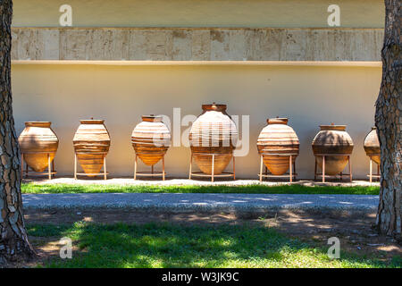 Huge earthenware jugs exhibited in the sun outside. Old pottery pots outside. Old orange clay jugs Stock Photo