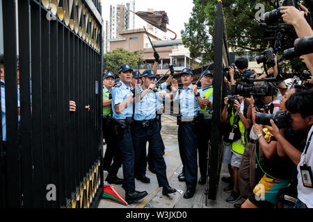 Photographers take pictures as police officers retreat behind a gate during a confrontation with protesters during anti-extradition bill demonstrations in Sheung Shui, Hong Kong on the 13th of July 2019. Pro-democracy protesters continue with demonstrations as they call for the complete withdrawal of a controversial extradition bill and the resignation of Hong Kong Chief Executive Carrie Lam. Stock Photo
