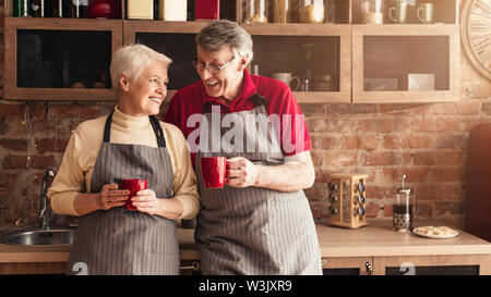 Cheerful seniors drinking morning coffee and talking at kitchen Stock Photo
