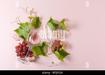 Assorted wineglasses with rose and white wine, grape, leaves and cork lying on pink background. Wine degustation concept. Flat lay. Top view. Copy spa Stock Photo