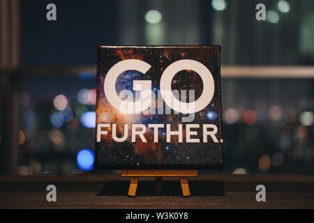 Typography on canvas space poster on top of easel "GO FURTHER" Stock Photo