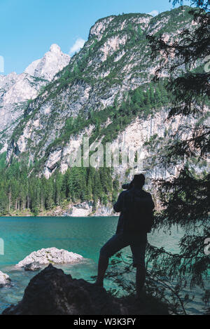 man climbing by rocks to shoot beautiful landscape of lake and mountains. photographer activities Stock Photo