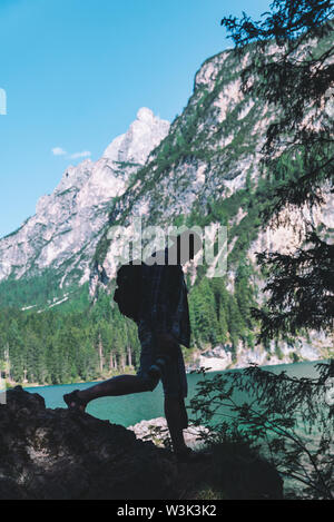 man climbing by rocks to shoot beautiful landscape of lake and mountains. photographer activities Stock Photo