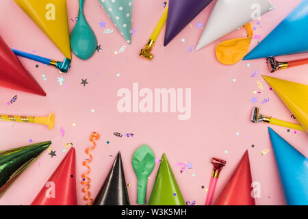 Top view of party horns, caps and confetti on pink background Stock Photo