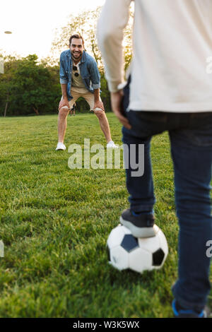 Two brothers playing football video game console, sitting on yellow pouf in  kids play center Stock Photo - Alamy