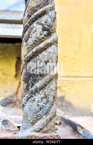 Decorative detail of the building in the form of a rusty cast-iron twisted post from the fence of the window. Old architectural element - a small deco Stock Photo