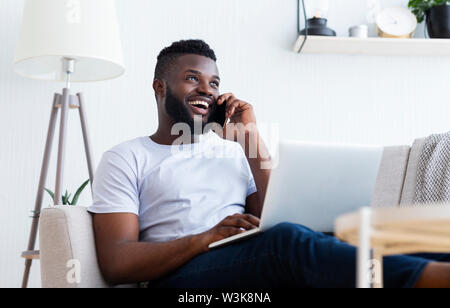 Young man talking on mobile phone and using laptop Stock Photo