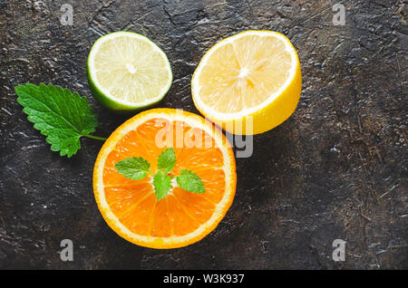 Slices of orange, lemon and lime with mint leaves on a concrete background. Stock Photo