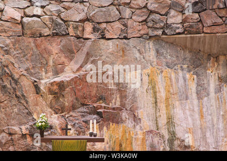 Modern minimalist altar with cross and two candles in front of rock wall in Temppeliaukio Church (Helsinki, Finland) Stock Photo