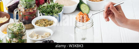 cropped view of woman adding couscous in glass jar on wooden white table, panoramic shot Stock Photo