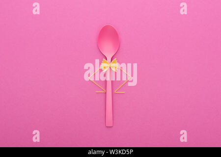 uncooked farfalle pasta on plastic spoon and spaghetti isolated on pink Stock Photo