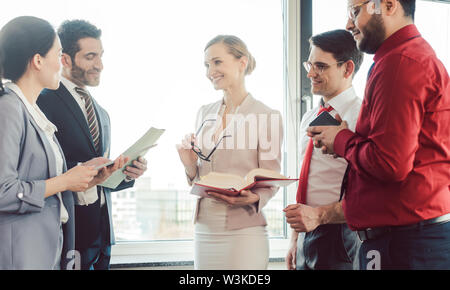 Business people standing by the window discussing a project Stock Photo