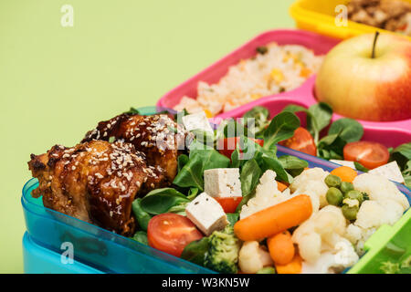 close up view of meal in lunch boxes isolated on green Stock Photo