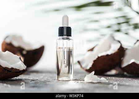 selective focus of glass bottle with coconut serum and dropper near cracked coconuts Stock Photo