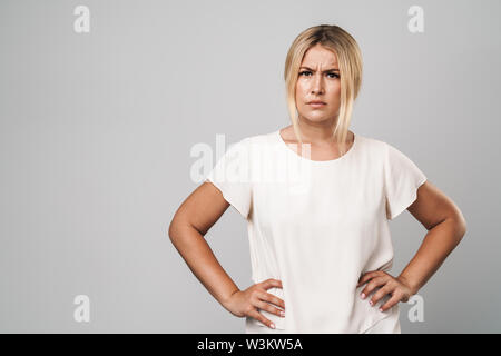 Portrait of an attractive frowning confused woman standing isolated over gray background Stock Photo
