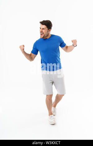 Full length photo of joyful man in shorts and t-shirt screaming and rejoicing with clenching fists isolated over white background Stock Photo