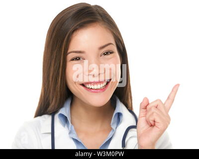 Doctor pointing. Female medical professional nurse or doctor showing copy space isolated on white background. Beautiful young Mixed race Asian / Caucasian woman model. Stock Photo