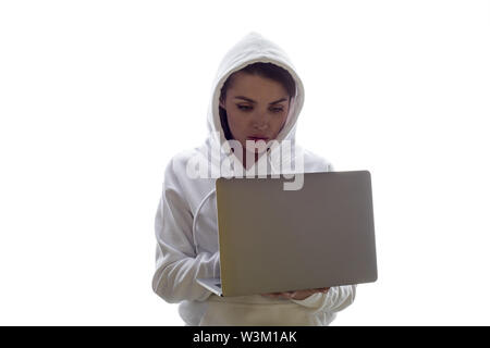 A woman in a hood is using a laptop. Hacker is using a laptop. Stock Photo