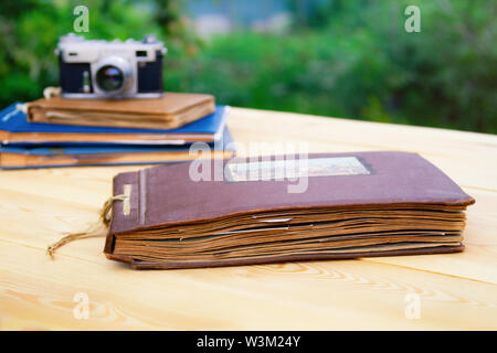 Old photo albums old camera on a light wooden table in the summer garden. Stock Photo