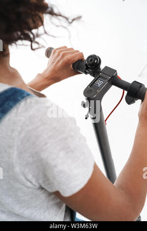 Cropped image of brunette african american woman riding electronic scooter with numbers on screen isolated over white background Stock Photo
