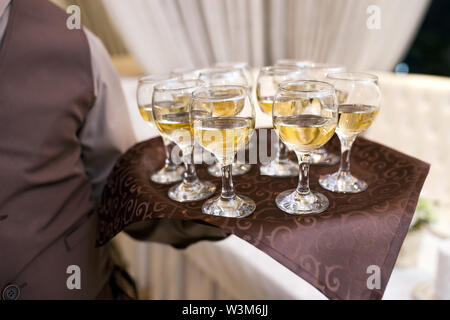 waiter with a tray welcomes visitors, filled glasses of wine Stock Photo