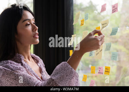 Businesswoman with adhesive notes on window Stock Photo
