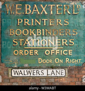 Old antique painted W.E. Baxter Ltd. Bookbinders and Stationers shop sign with faded gold lettering on brick wall Walwers Lane, Lewes, East Sussex, UK Stock Photo