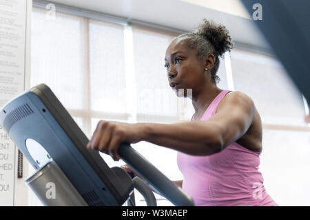 Mature woman exercising on elliptical machine Stock Photo