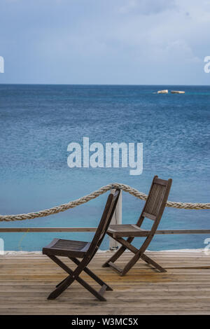 Wooden chairs on a deck platform in Agios Nikolaos beach on Zakynthos Island, Greece Stock Photo