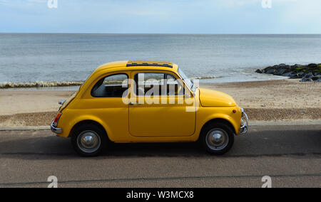 Classic Yellow Fiat 500  Automobile parked on seafront promenade . Stock Photo