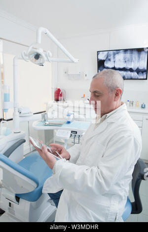 Dentist using digital tablet in dentist's surgery Stock Photo