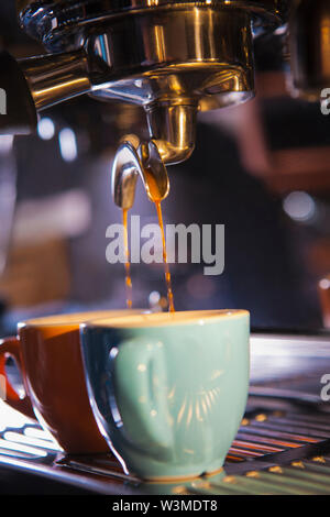 Coffee pouring from portafilter into coffee cups Stock Photo