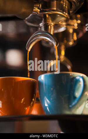 Coffee pouring from portafilter into coffee cups Stock Photo