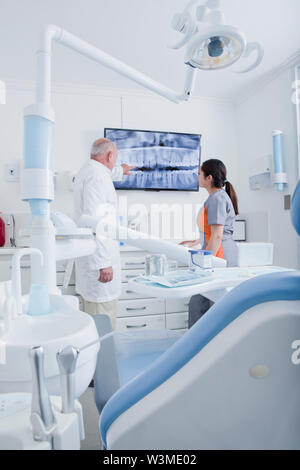 Dentist and dental hygienist examining X-ray on television screen Stock Photo