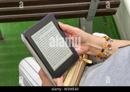 LAKE COMO, ITALY - JUNE 2019: Person reading an e reader while sitting on the deck of a ferry on Lake Como. Stock Photo