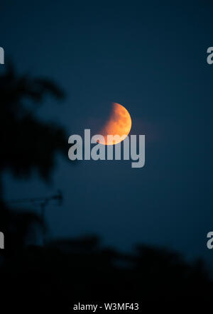 Wimbledon, London, UK. 16th July 2019. On the 50th anniversary of the Apollo 11 takeoff on the historic manned flight to the lunar surface a partial lunar eclipse of the full moon is visible from the UK, with the greatest eclipse visible at 22:30 BST. Credit: Malcolm Park/Alamy Live News. Stock Photo
