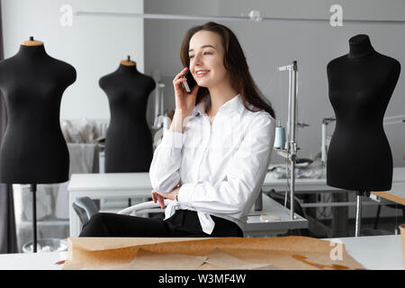 Fashion designer talking on smartphone in studio Stock Photo