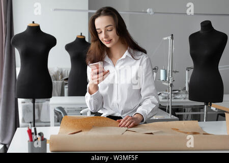 Fashion designer using smartphone in studio Stock Photo