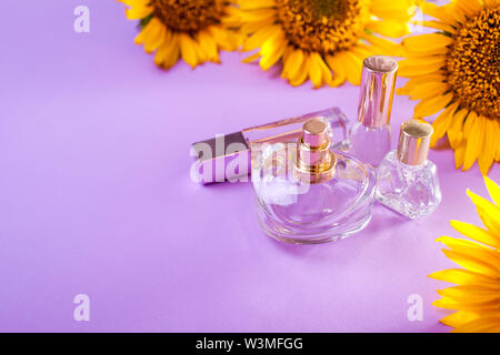 Bottles of perfume with sunflowers on purple background. Organic cosmetics. Natural ingredients Stock Photo