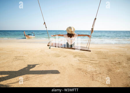 Young woman on swing at beach Stock Photo