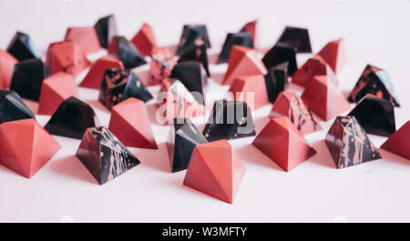 Dark chocolate pralines on pink background, colored in black and coral. Stock Photo